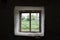 View from old scary window with a web on the street in the dark. Window view of an abandoned old house, building, barn