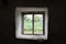 View from old scary window with a web on the street in the dark. Window view of an abandoned old house, building, barn