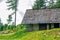 View of the old stone house with wooden damaged roof on the meadow