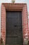 View of the old wooden door, forged metal hinges, locks, beautiful decorative finish outside with brick. Architecture, elements