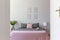 A view through an open door into a pastel bedroom interior with ashy bedding and rosy blanket on a double bed. Nature illustration