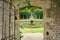 the view from an open gated doorway leads out to a fountain and a lily pond