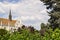 View of ornately colored tile roof of St. Matthias Church through the lush greens of trees on cloudy sky background.