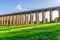 A view of the Ouse Valley Viaduct Balcombe Viaduct in the summer with bright sun shining through the arches onto the grass