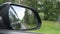 View out the rearview mirror as car drives on country road