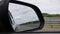 View out the rearview mirror as car drives on country road