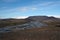 View over barren waste black plain with creek on partly snow capped mountains in the horizon - Iceland