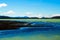 View over black volcanic sand beach on remote  blue and green shimmering water against blue sky