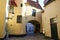 View over cobblestone courtyard on small yellow medieval castle with street lamp, tower, entrance arch - Brugge, Belgium