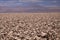 View over endless bright white and brown barren salt plateau into blurred horizon contrasting with deep blue sky