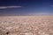 View over endless bright white and brown barren salt plateau into blurred horizon contrasting with deep blue sky