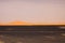 View over endless burned black flat waste stony land on golden sand dunes and blurred gloomy sky, Erg Chebbi, Morocco