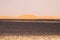 View over endless burned black flat waste stony land on golden sand dunes and blurred gloomy sky, Erg Chebbi, Morocco