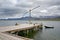 View over the fjord with a wooden jetty, fishing boat, and beautiful mountains & islands in the background, Eskifjordur, Iceland.