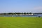 View over green meadow and river Maas on island with campsite against blue summer sky