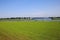 View over green meadow and river Maas on island with campsite against blue summer sky