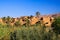 View over green plants and palm trees on isolated clay house village against blue sky