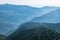 View over the Green Valley, surrounded by high mountains on a summer sunset. Layers of mountains in the haze during sunset