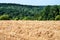 View over harvested field to hilly forest