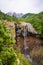 View over Mangawhero Falls rushing down from 20m height of the rocks into a small river. Magnificent peaks of Mt Ruapehu