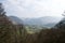 View over a pastoral valley; mountains, bare winter trees, green fields