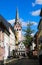 View over pedestrian zone on white medieval timbered house with catholic church clock tower in summer with blue sky