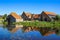 View over reflecting river pond on old water mill restaurant against deep blue cloudless summer sky - Neer Limburg, Netherlands