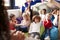 View over the shoulder of infant school teacher showing a book to a group of children sitting on bean bags in a comfortable corner