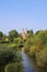 View over small river Roer with green trees on roman catholic basilica with monastery from 11th century against blue summer sky