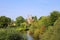 View over small river Roer with green trees on roman catholic basilica with monastery from 11th century against blue summer sky -