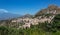 View over the terracotta rooftops of Taormina with steaming Etna in the background, Sicily, Italy