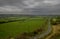 A view over undulating farmland with a road leading away from the camera.