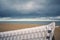 View over an unfocussed beach chair to a lonely beach on overlooking the sea to dramatic looking storm clouds