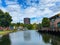 View over water canal beyond beach on gasometer tower against summer sky