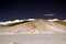 View over white barren salt plain on cone shaped white and brown colored bare mountain contrasting with deep blue sky