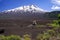 View over wide field of volcanic lava ash on peak of black Volcano Llaima with spots and stripes of snow and ice