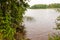 View from the overgrown beach on floating eight rowing boat in the waters of Galve lake surrounded by green forest