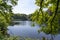 A view between the overhanging branches with fresh leaves, over the pond in the park De Horsten in Wassenaar, the Netherlands