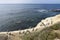 A view of Pacific Ocean and coast with some grass. Pelicans sitting on sandy coast