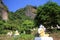 View on  Park with countless sitting Buddha statues in a row between trees against rock face and blue sky