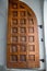 View of a part of an old wooden gate in the form of brown squares against a white wall. Architecture, elements