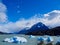 View of a Patagonian lake with ice blocks floating around, mountains and clouds
