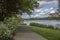 View of a path next to a lake with trees and green vegetation