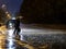 View of a pedestrian crossing in the city at night during a heavy downpour. Silhouettes of people with umbrellas.