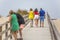 View of pedestrian path on beach, backs of couple with daughter walking on wooden path and other couple talking