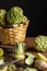 View of peeled artichoke on table with limes, knife and basket with artichokes, on wooden table and black background,