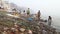 View on people going through waste at dirty shore of river Ganges.