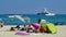 View on people relaxing on sand beach, mediterranean sea with yachts background focus on lower third