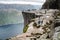 View of people walking on Preikestolen Pulpit Rock from distance with a fjord underneath