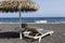 view of Perissa beach on the Greek island of Santorini with sunbeds and umbrellas. Beach is covered with fine black sand, and